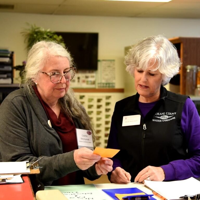 Master Gardener showing an intern how to record plant information.